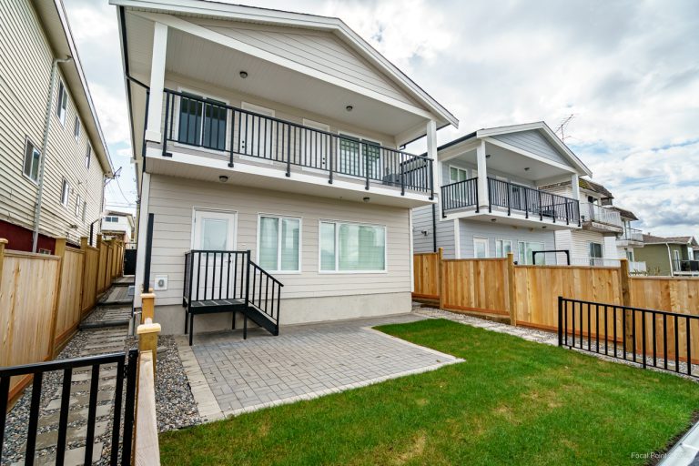 Backyard featuring aluminum railing, cedar fencing, fresh sod, hardscaping, grass areas, and decorative river rock landscaping.