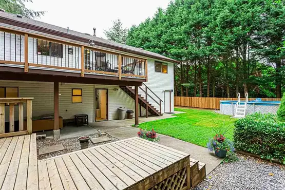 Backyard featuring a custom-built deck with a hot tub and a beautifully finished concrete hosting area.