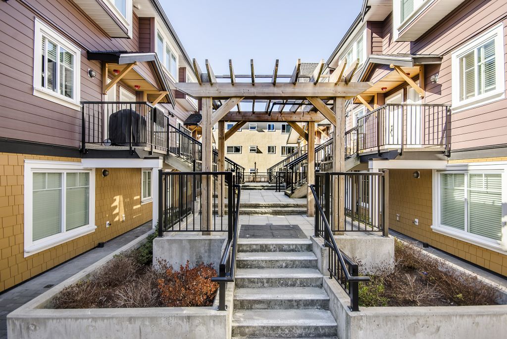 Townhome complex landscaping in New Westminster, British Columbia featuring concrete paver walkways, modern concrete planters, and native plants with connected private pedestrian pathways.