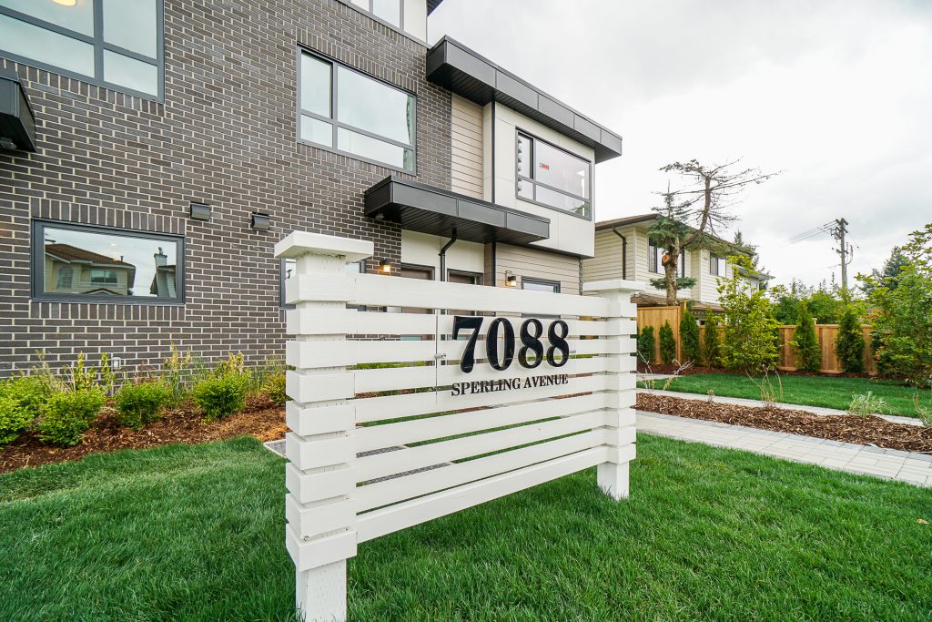 House sign on grass in Coquitlam, in a multiplex front yard with a small fresh sod area and clean, simple landscaping.