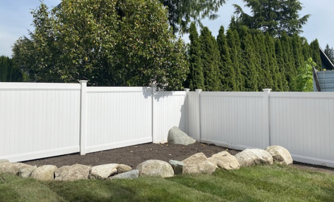 White vinyl fence in Port Moody with a large decorative rock feature.
