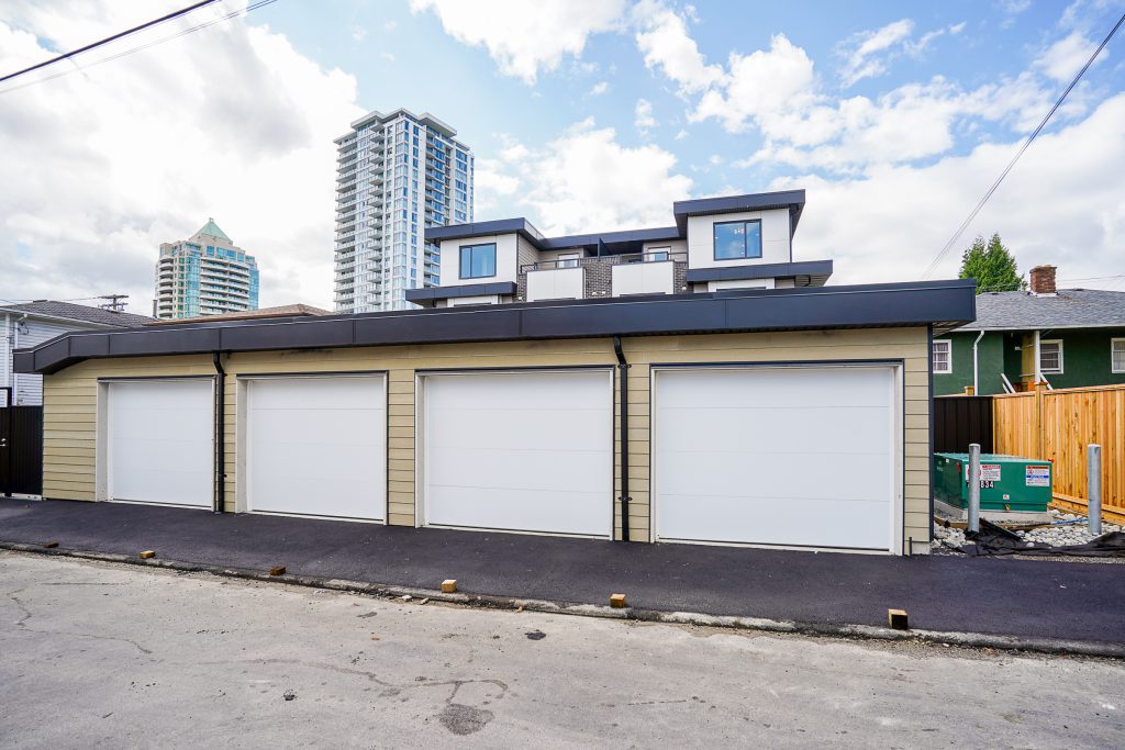 Burnaby multiplex with four garages and a newly poured asphalt surface in the rear alley for vehicle access.