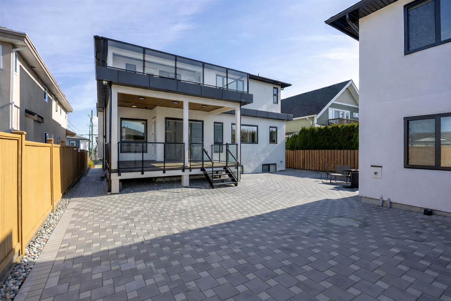 Interlocked paver backyard in Burnaby featuring rear access, a parking pad, and a multifunctional hosting area.