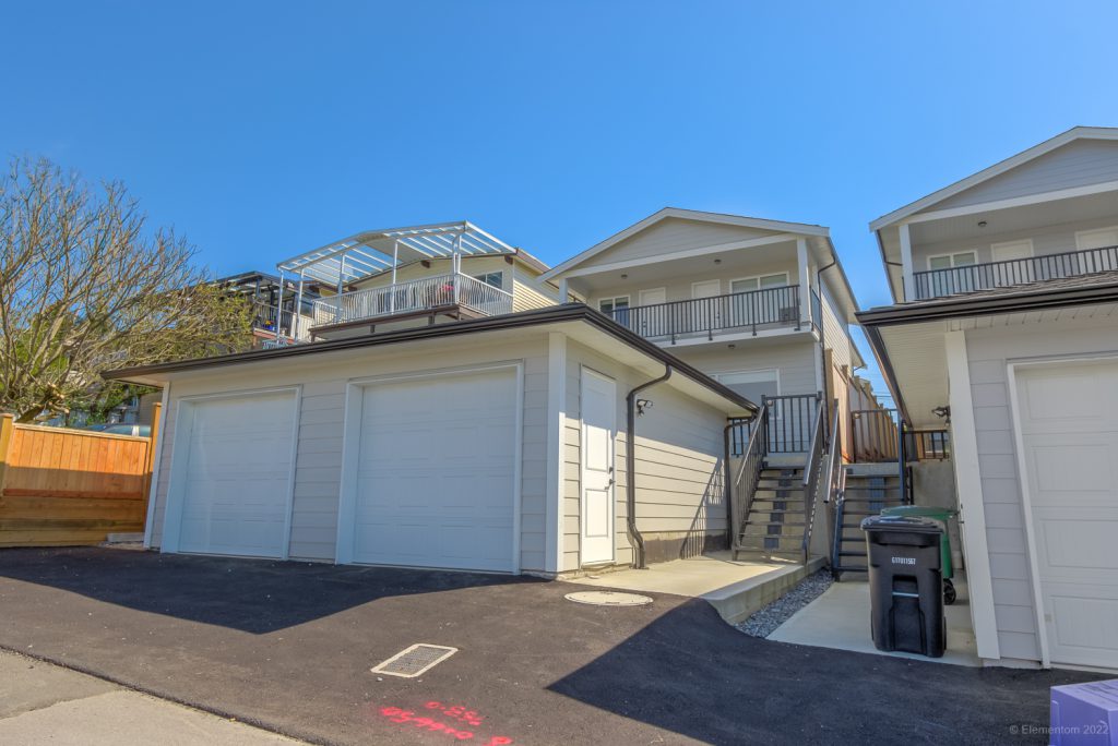 Vancouver duplex with a freshly paved asphalt alley leading to the garage for vehicle access.